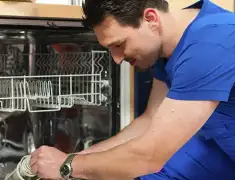 Dishwasher repair technician inspecting and servicing an open dishwasher in Lincoln, NE