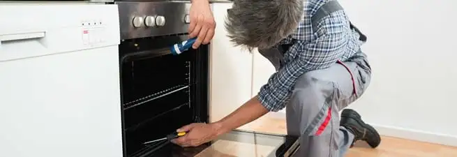 Oven repair technician inspecting and servicing an electric oven in Lincoln, NE