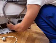 Appliance repair technician fixing refrigerator water line and connections in Lincoln, NE