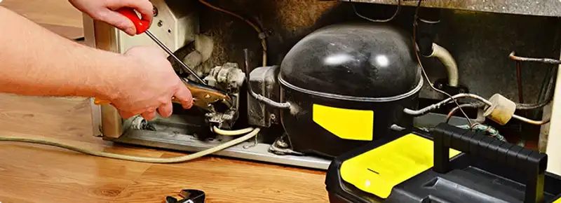 Refrigerator repair technician fixing the compressor and wiring in Lincoln, NE