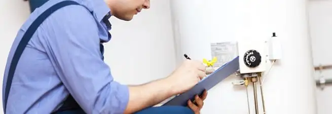 Water heater repair technician inspecting the unit and recording service notes in Lincoln, NE